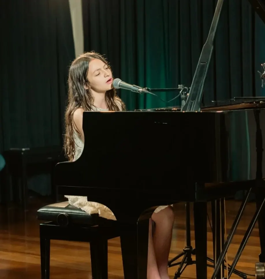 Aluna da Portato cantando e tocando piano ao vivo